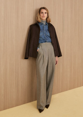 Dark brown wool jacket draped over the shoulders, medium-wash denim shirt over a grey turtleneck, high-waisted wide-leg trousers in a micro checked pattern, and pointed shoes