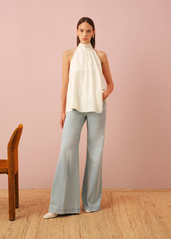 A half-length portrait of a woman wearing a light mint green tank top with a V-neck, paired with matching textured shorts featuring an elastic waistband and a cream drawstring