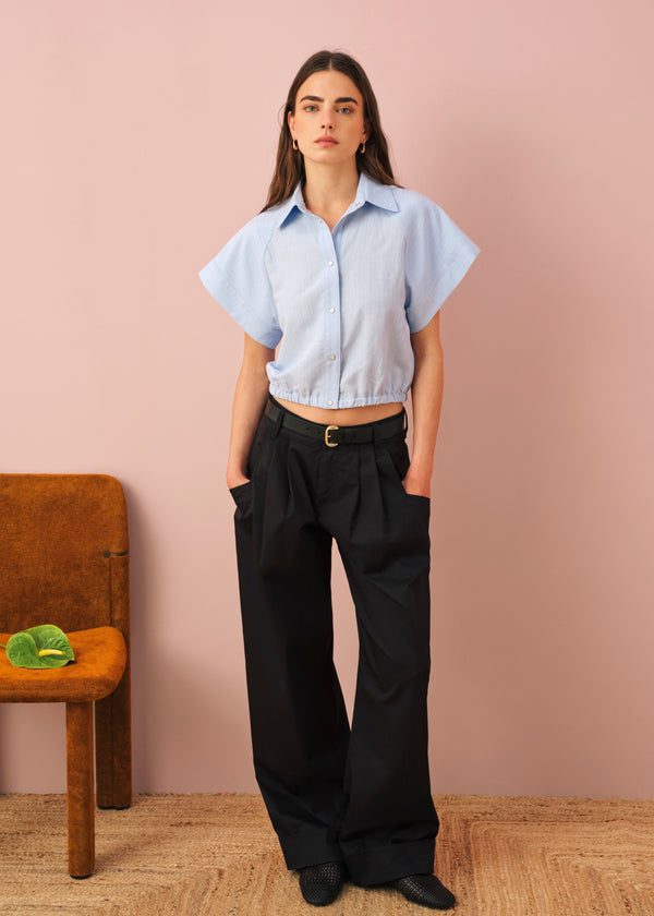 Woman wearing light blue cropped shirt and blue wide-leg trousers