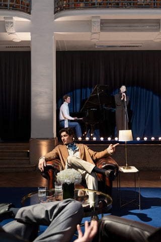 Five star hotel lounge: a man in smart casual attire sits relaxed in the foreground on a burgundy leather Chesterfield armchair