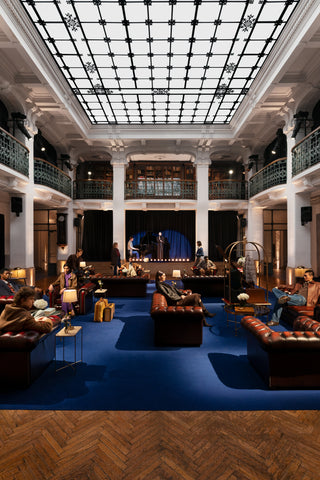 Main hall of a five-star hotel in a classic style: a geometric glass ceiling with floral decorations, white columns, and two-level balconies with wrought-iron railings