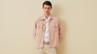 Man wearing blush pink shirt jacket over white button-up shirt with beige belt, cream pants