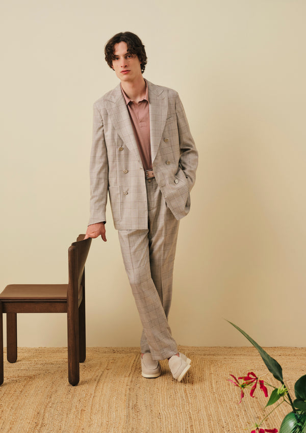 Man wearing a beige Glen plaid double-breasted suit over a dusty pink polo shirt and beige loafers